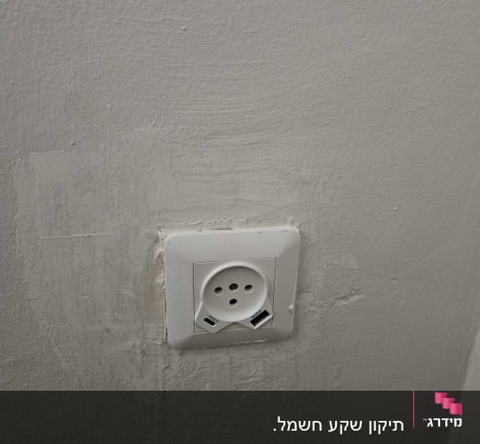 שקע חשמלי מותקן על קיר אפור